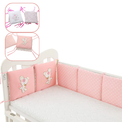 Berceau avec un tour de lit bébé fille rose décoré de motifs à pois blancs dont deux coussins ornés d'un ourson brode