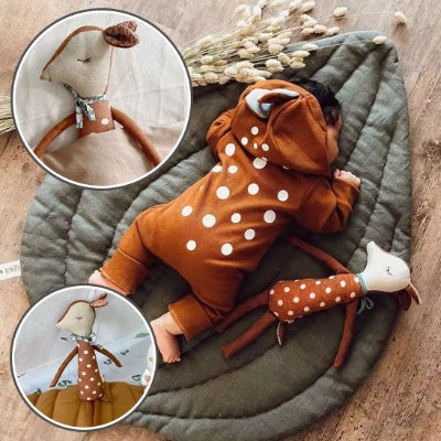 bébé allongé sur son ventre avec son doudou biche pour une prise de photo