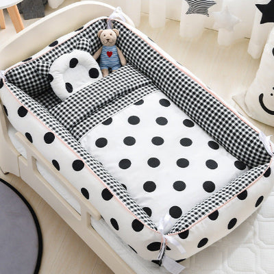 réducteur de lit bébé CoconÉvolutif™ à motif dots posé dans le lit de bébé