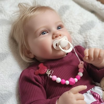 Allongée, la fillette a sa tétine bien fixée à son habit grâce à son attaché tetine Biiikylip™ rose