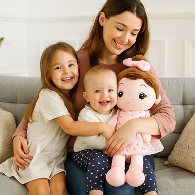 Assise sur le canapé, maman serre ses filles contre elle, leur poupée de chiffon dans les bras, un grand sourire illumine leurs visages.