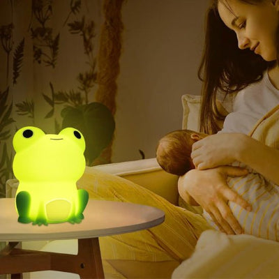 Assise sur le lit, maman allaite tendrement son bébé, éclairée par la douce lumière de la veilleuse bébé posée sur la table de nuit