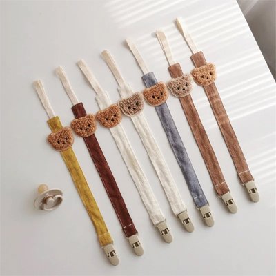Attache tetines avec une tête d’ours, aux couleurs blanc, brun et jaune