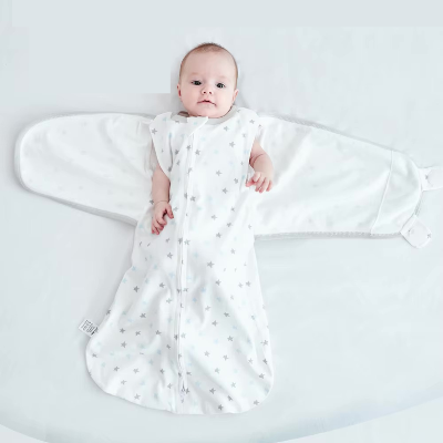 Bébé allongé dans une gigoteuse emmaillotage étoilée.