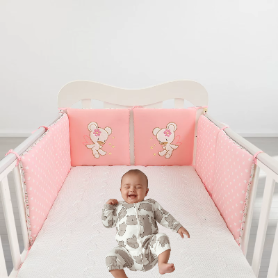 Bébé allonge dans son lit entouré d'un tour de lit bébé fille rose doux avec coussins ourson brodes