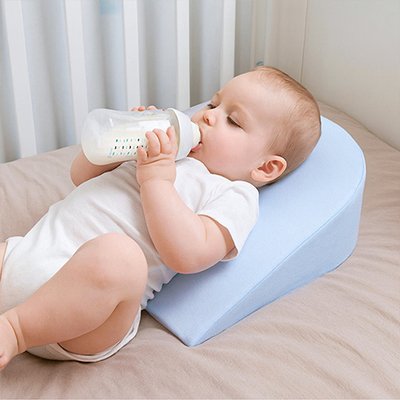  Bébé allongé sur le dos buvant son biberon sur un plan incliné bébé Anti-Reflux 15° DreamerBaby™ bleu
