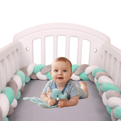 Bébé câlinant son doudou, entouré d'une tresse tour de lit aux tons vert, blanc et gris sécurisante.