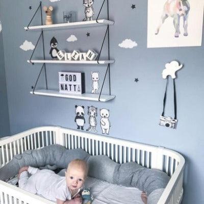 Bébé sur le ventre redresse la tête dans son lit entoure d'un tour de lit pour bebe en forme de crocodile créant un véritable cocon de douceur