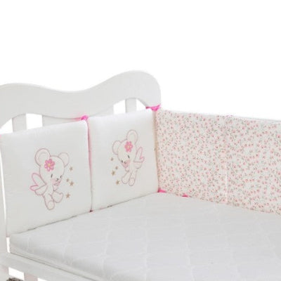 Berceau décoré d'un tour de lit bébé fille blanc aux motifs fleuris avec deux coussins ornés d'un ourson brode