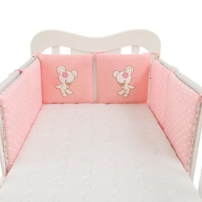 Berceau décoré d'un tour de lit bébé fille rose mêlant pois blancs et coussins brodés d'un ourson