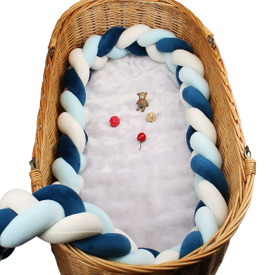 Dans un couffin en osier, un tour de lit tresse aux tons bleus et blancs entoure délicatement l'espace de couchage du bébé.