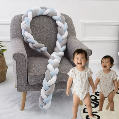 Deux tout petits souriants se tiennent debout près d'un fauteuil gris sur lequel est posée une longue tresse de lit 4 m décorative bleu blanc et gris