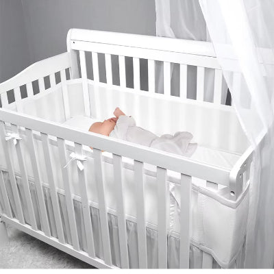 Endormi dans son berceau, bébé est enveloppé d'un tour de lit respirant blanc qui lui créé un havre de douceur