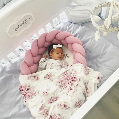 Fillette allongée dans un reducteur de lit pour bebe SweetSnug™ rose, placé à l'intérieur du lit à barreaux