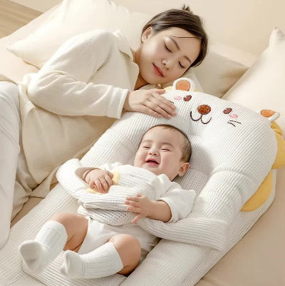 Moment complice : maman fait la sieste auprès de son bébé qui dort paisiblement dans son reducteur de lit bebe HeatPad™