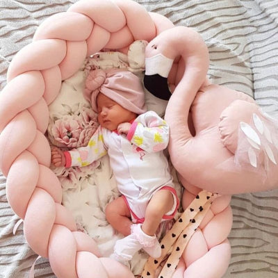 Petite fille endormie dans  son reducteur de lit pour bebe SweetSnug™ rose, accompagnée de son fidèle doudou cygne