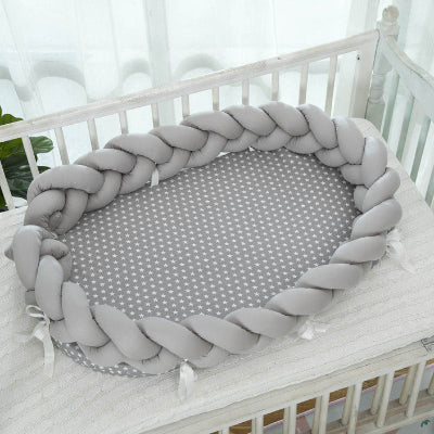 Reducteur de lit pour bebe SweetSnug™ gris, disposé dans le lit à barreaux blanc.