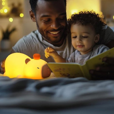 Sous la lueur apaisante de la veilleuse, le papa lit à son fils, le visage éclairé d’un grand sourire.