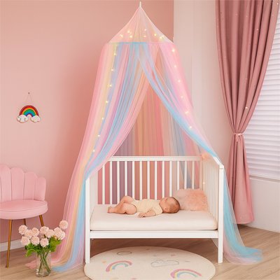 Suspendue au-dessus du lit, la moustiquaire ciel de lit bébé multicolore enveloppe le bébé endormi dans une atmosphère calme et rassurante.
