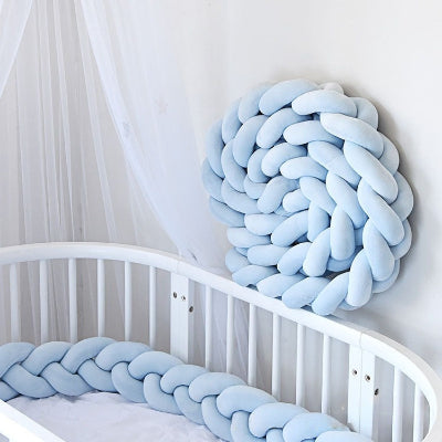 Tour de lit tresse bleu pastel installé sur le lit et un autre en forme de cercle accroché au mur pour créer un nid douillet pour le bébé.