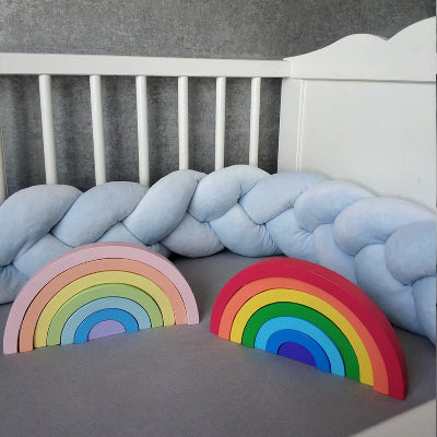 Tour de lit tresse bleu pastel sur le lit avec deux arcs-en-ciel en bois au centre pour un lit cosy et plein de charme