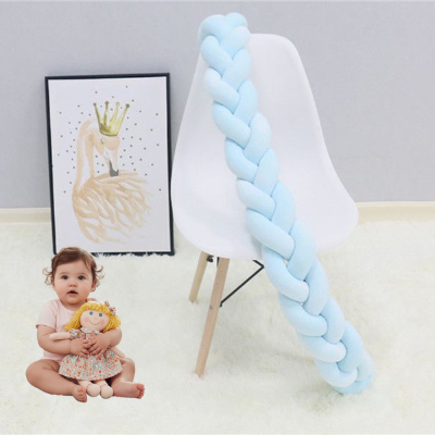 Tresse de lit bebe posée sur une chaise blanche avec une fillette jouant sur le tapis à côté son doudou serre dans les mains