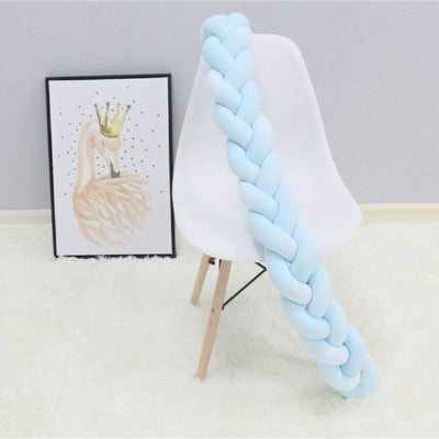 Tresse de lit pour bebe posée sur une chaise blanche sur un tapis blanc