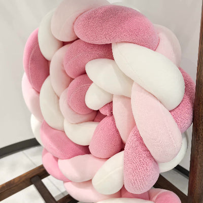 Tresse tour de lit aux douces teintes rose et blanc posée sur un tabouret