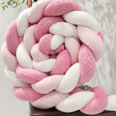 Tresse tour de lit aux teintes rose et blanc enroulée en boule et posée sur un tabouret