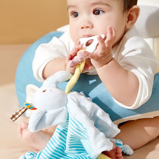 Bébé assis son doudou bébé éléphant dans ses mains