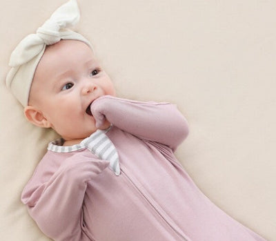 Un bébé détendu est enveloppé dans une gigoteuse emmaillotage violette, créant un véritable cocon de douceur et de bien-être.