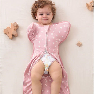 le bébé est confortablement emmitouflé dans une turbulette gigoteuse rose décorée de cœurs.