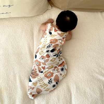 Un bébé à quatre pattes porte une gigoteuse ornée de motifs floraux.
