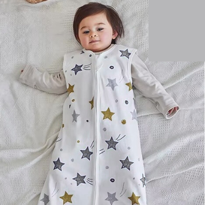 Un bébé repose paisiblement, enveloppé dans une gigoteuse turbulette blanche aux motifs d'étoiles.