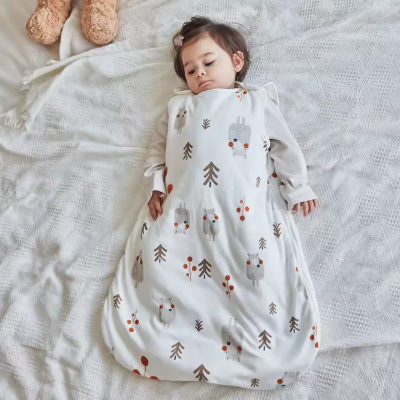 Un bébé repose sur un lit dans une gigoteuse turbulette blanche à motifs d’ours