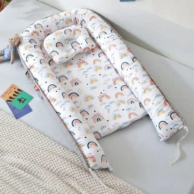 Berceau Bébé NidPortableBébé™ Arc En Ciel  est déposé sur le lit