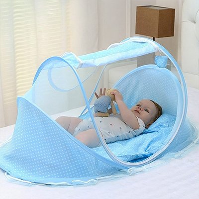 Enfant allongé joue avec son doudou dans le lit moustiquaire bébé