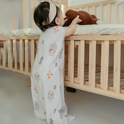 Un enfant debout devant son lit prend son doudou, habillé d’une gigoteuse turbulette blanche aux adorables motifs d’ours