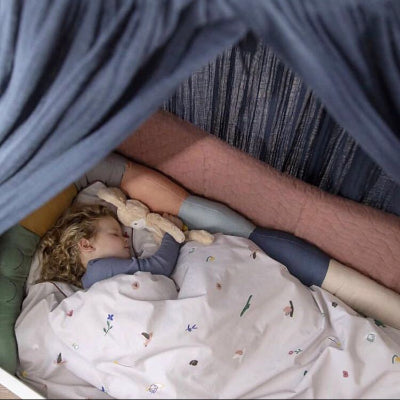 Un enfant endormi dans son lit au milieu d'un tour de lit colore en forme de crocodile