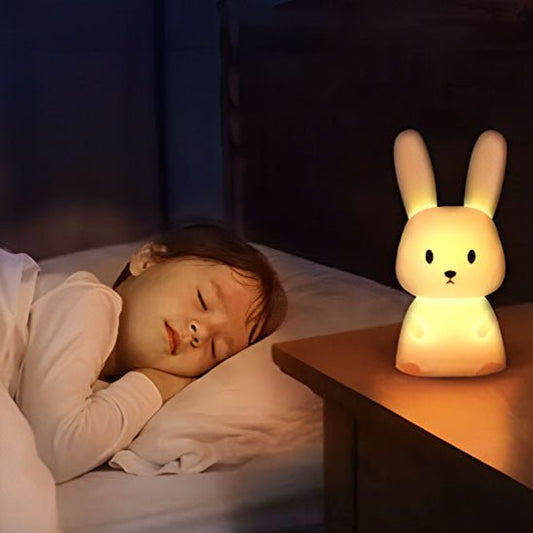 Un enfant endormi paisiblement sous la lumière de sa veilleuse bébé Glowbit™ en forme de lapin