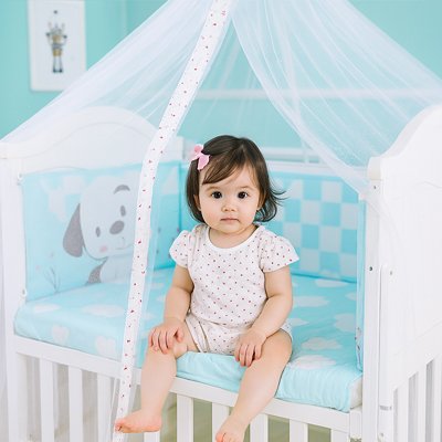 fillette assise au bord du lit moustiquaires lit bébé