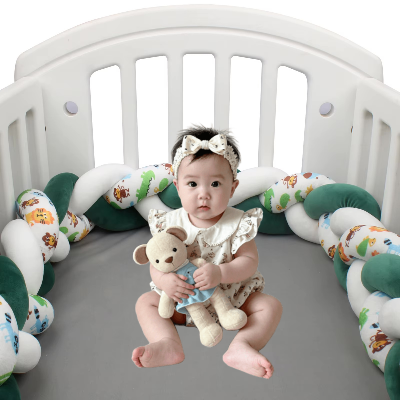 Une fillette assise dans son lit avec son doudou entourée d'une tresse de lit cabane verte, blanche et a motifs d'animaux qui crée un cocon rassurant.