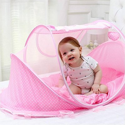 fillette souriante assise dans le lit moustiquaire bébé