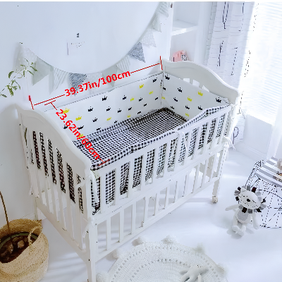 Le lit bébé blanc est protégé par un tour de lit pour bebe orne de délicates petites couronnes