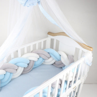 Un lit bébé blanc au style délicat habillé d'une tresse de lit bebe turquoise blanc et gris créant un cocon doux et apaisant sous un voile léger
