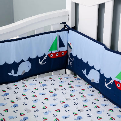 Le lit bébé est entouré d'un tour de lit bebe garcon colore sur le thème marin illustre de bateaux, de pieuvres et de baleines créant un univers à la fois sécurisé et amusant.