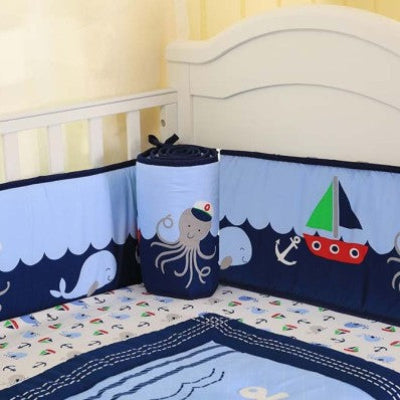 Le lit bébé est entouré d'un tour de lit bebe garcon décoré de bateaux, d'animaux marins et de vagues offrant un espace sécurisé et amusant.