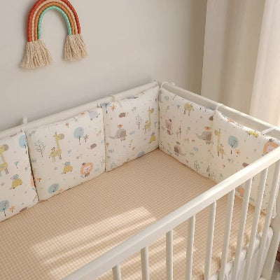 Le lit bébé est entouré d'un tour de lit bebe rembourre décoré d'adorables motifs d'animaux de la foret créant un espace doux et sécurisé.