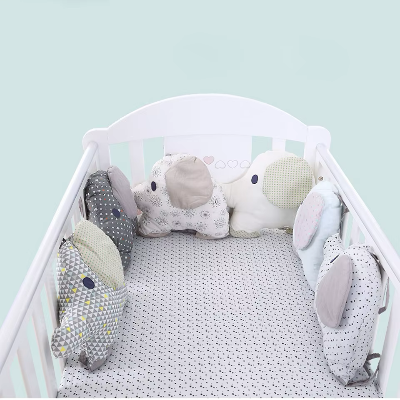 Le lit de bébé est décoré d'un tour de lit bébé compose de coussins éléphants places tout autour
