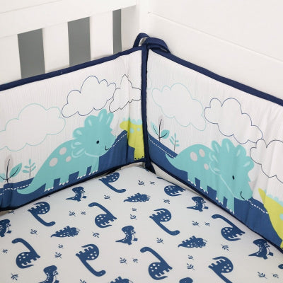 Le lit bébé est équipé d'un tour de lit bebe garcon colore avec de mignons dinosaures assortis à un drap blanc imprime de petits dinosaures bleus créant une ambiance ludique et joyeuse.